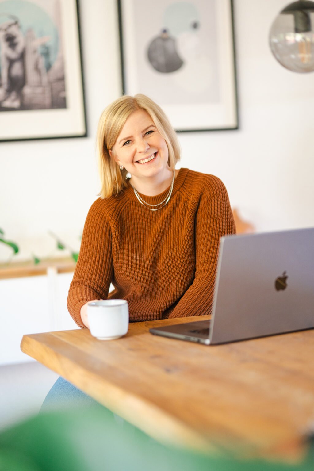 Nadine Hansen sitzt am Tisch und schaut lächelnd in die Kamera.